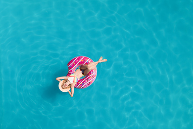 Young happy woman with inflatable ring in swimming pool, top view. Summer vacation