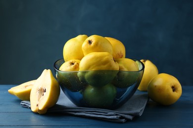 Photo of Tasty ripe quinces in bowl on blue wooden table