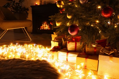 Photo of Beautiful Christmas tree, fairy lights and gifts indoors