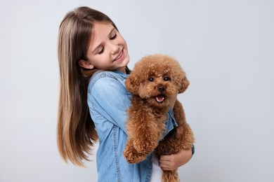 Photo of Little child with cute puppy on light grey background. Lovely pet