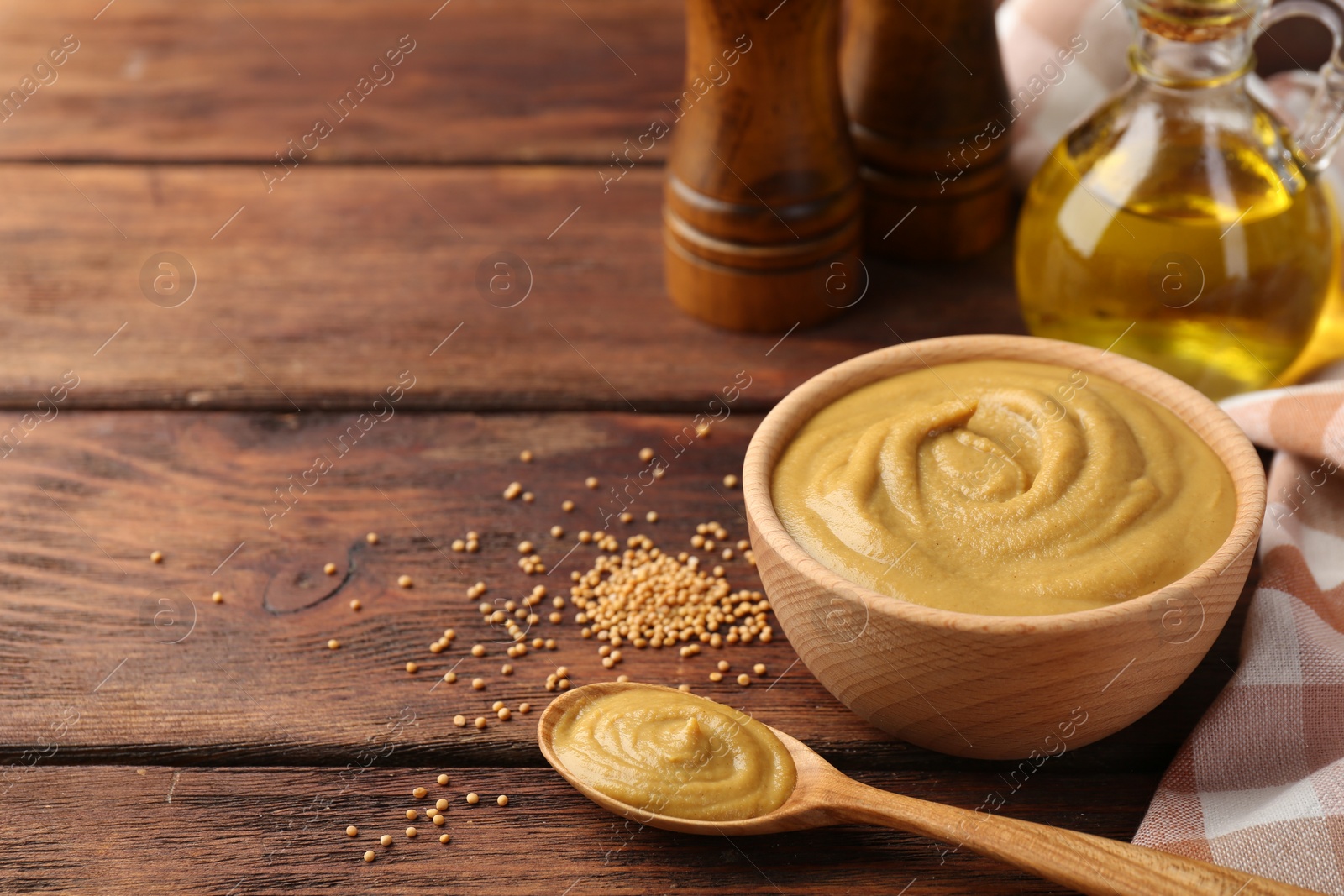 Photo of Tasty mustard sauce and dry seeds on wooden table, space for text