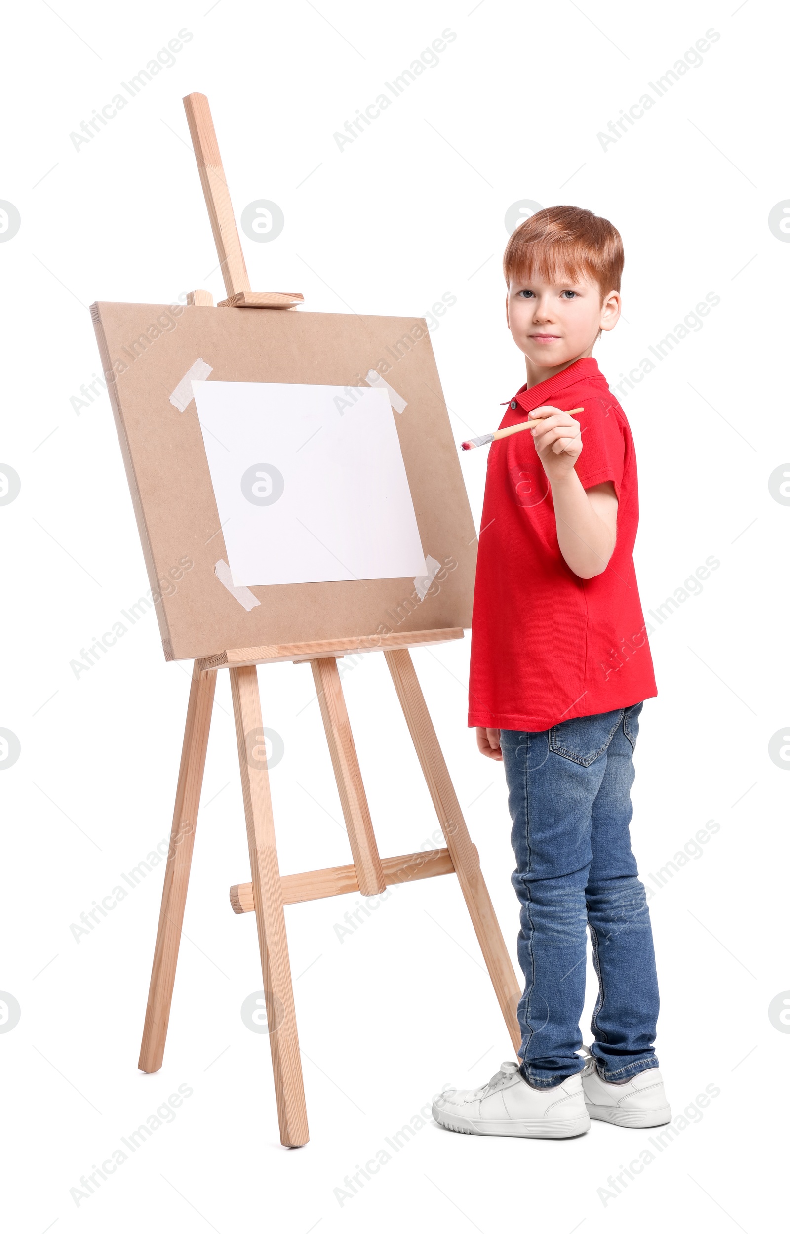 Photo of Little boy painting against white background. Using easel to hold canvas
