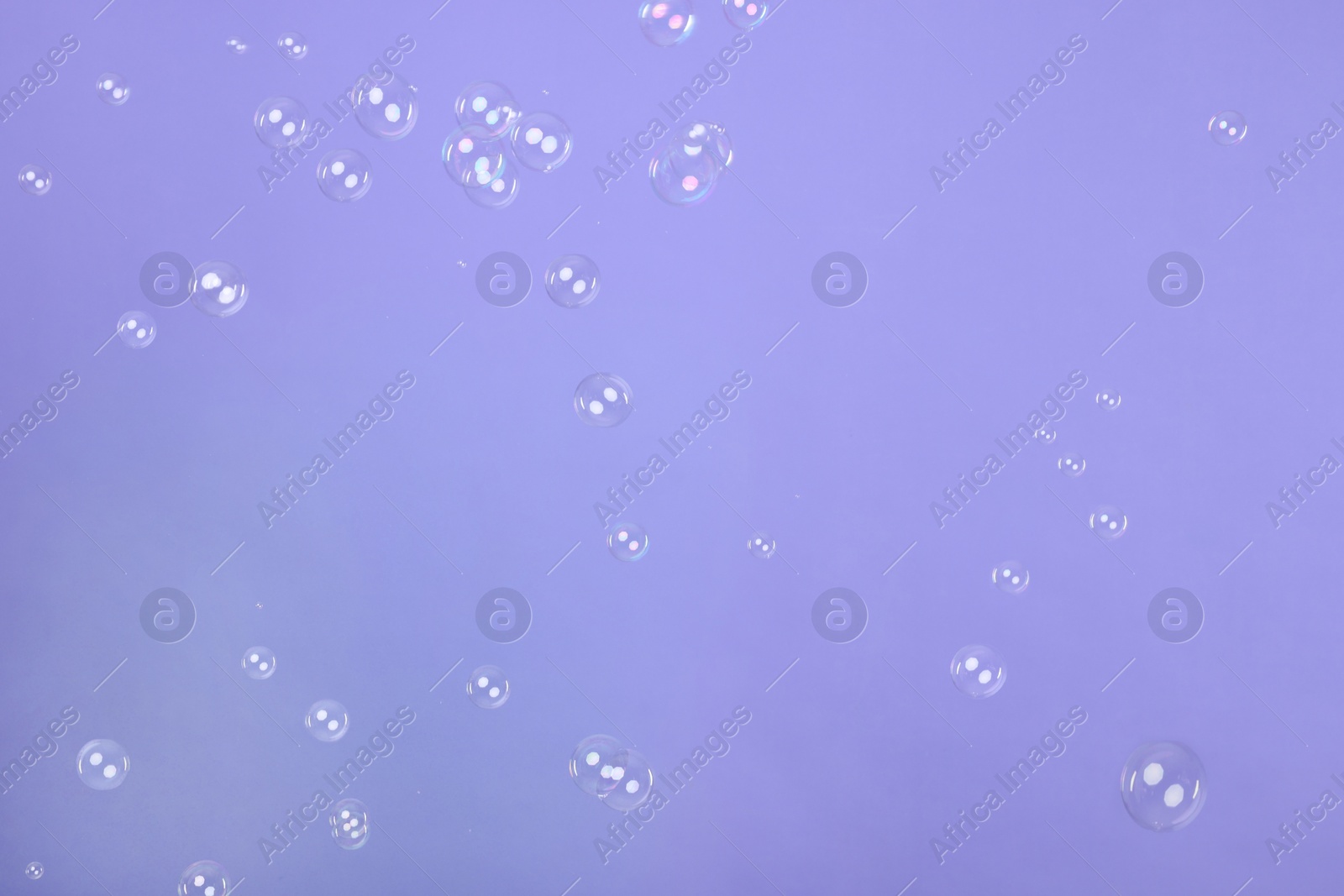 Photo of Many beautiful soap bubbles on violet background