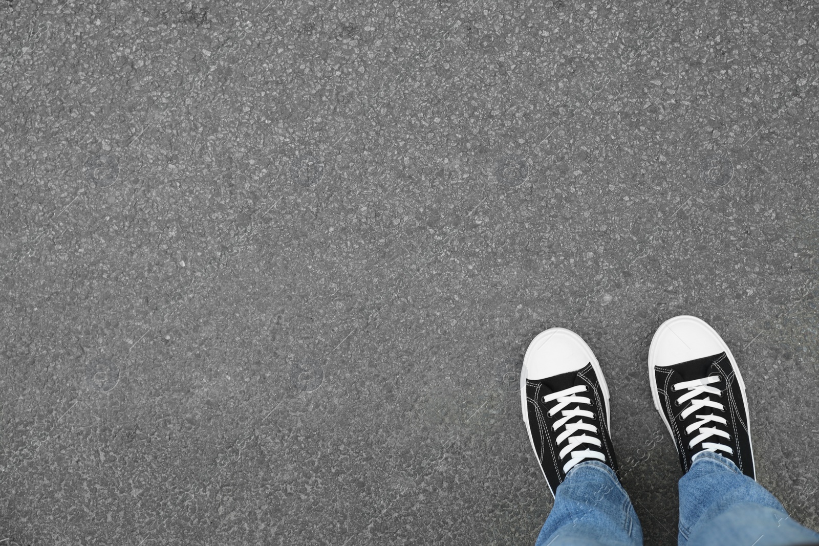 Photo of Man in sneakers standing on asphalt, top view. Space for text