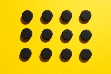 Photo of Activated charcoal pills on yellow background, flat lay. Potent sorbent