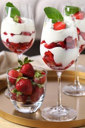 Photo of Delicious strawberries with whipped cream on wooden table indoors