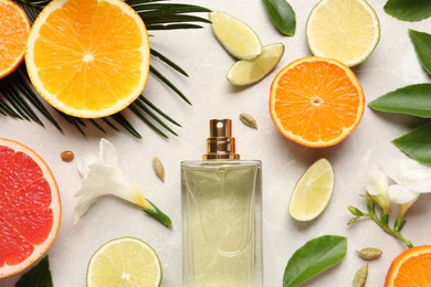 Flat lay composition with bottle of perfume and fresh citrus fruits on light marble background