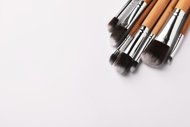 Photo of Set of makeup brushes on white background, above view. Space for text