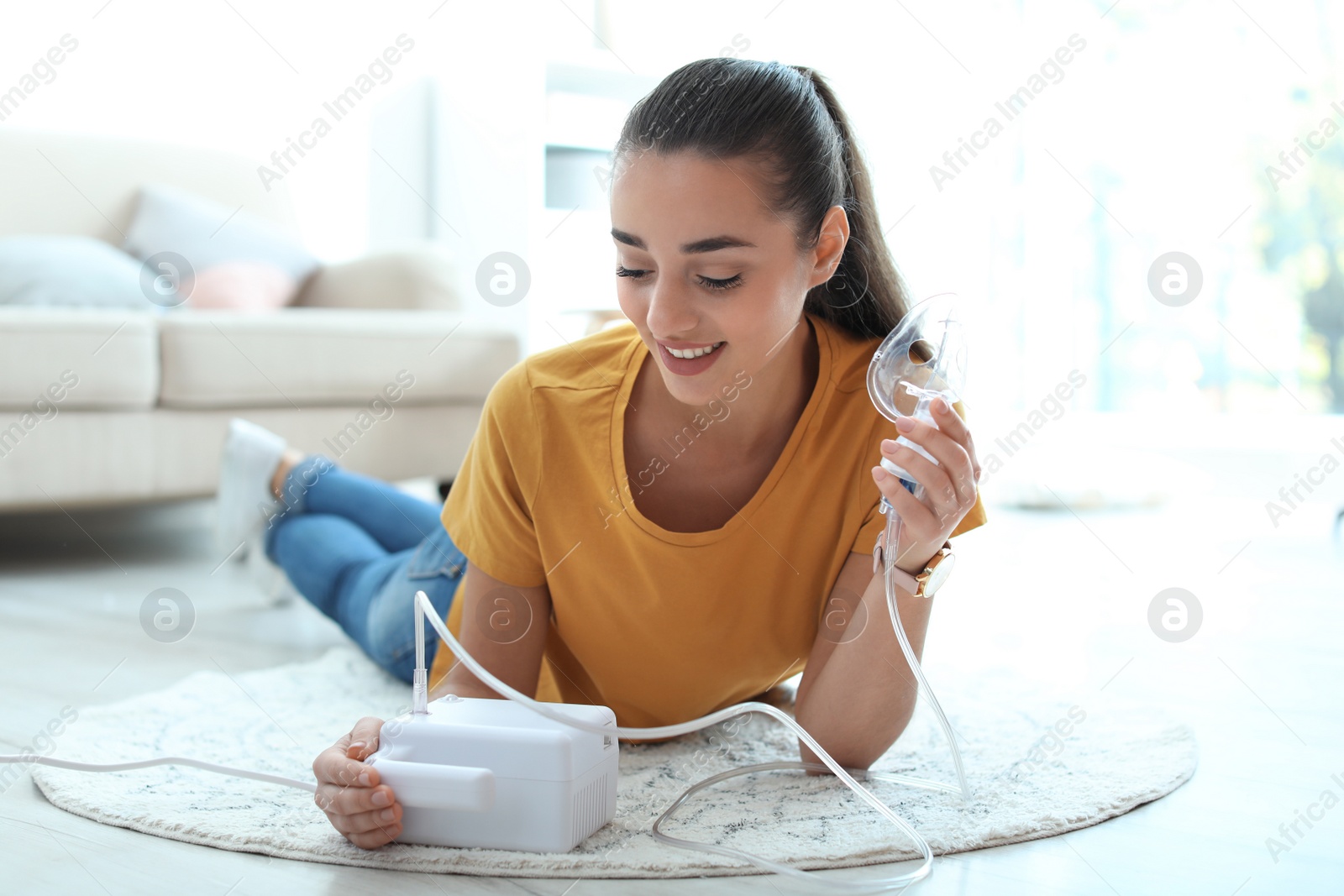 Photo of Young woman using asthma machine at home. Health care