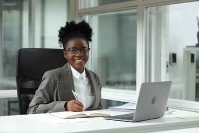 Photo of Happy woman working at table in office. Lawyer, businesswoman, accountant or manager