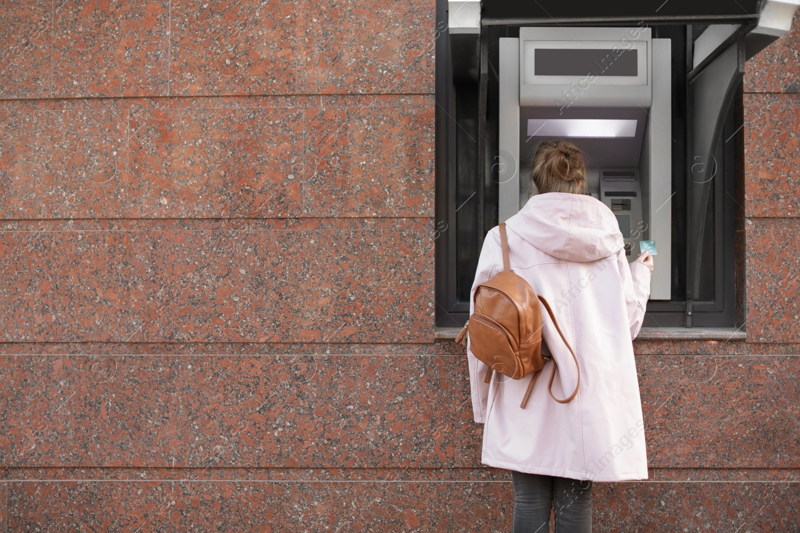 Photo of Young woman with credit card near cash machine outdoors. Space for text