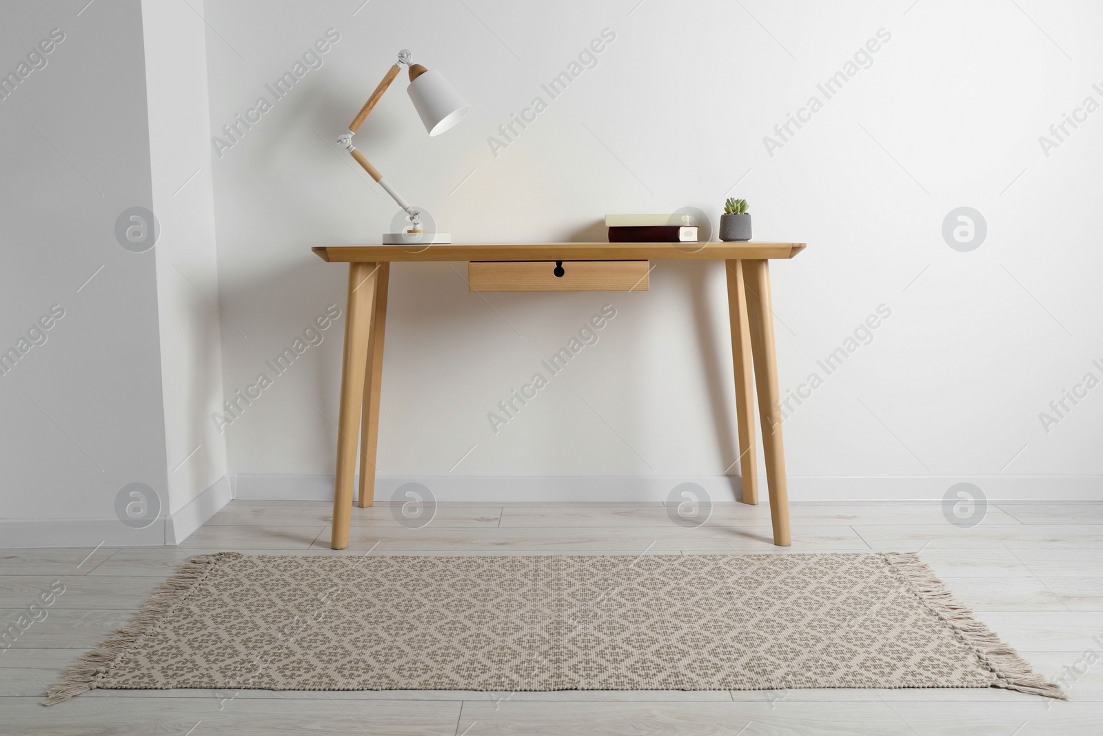 Photo of Stylish lamp, books and houseplant on wooden table in light room. Interior design