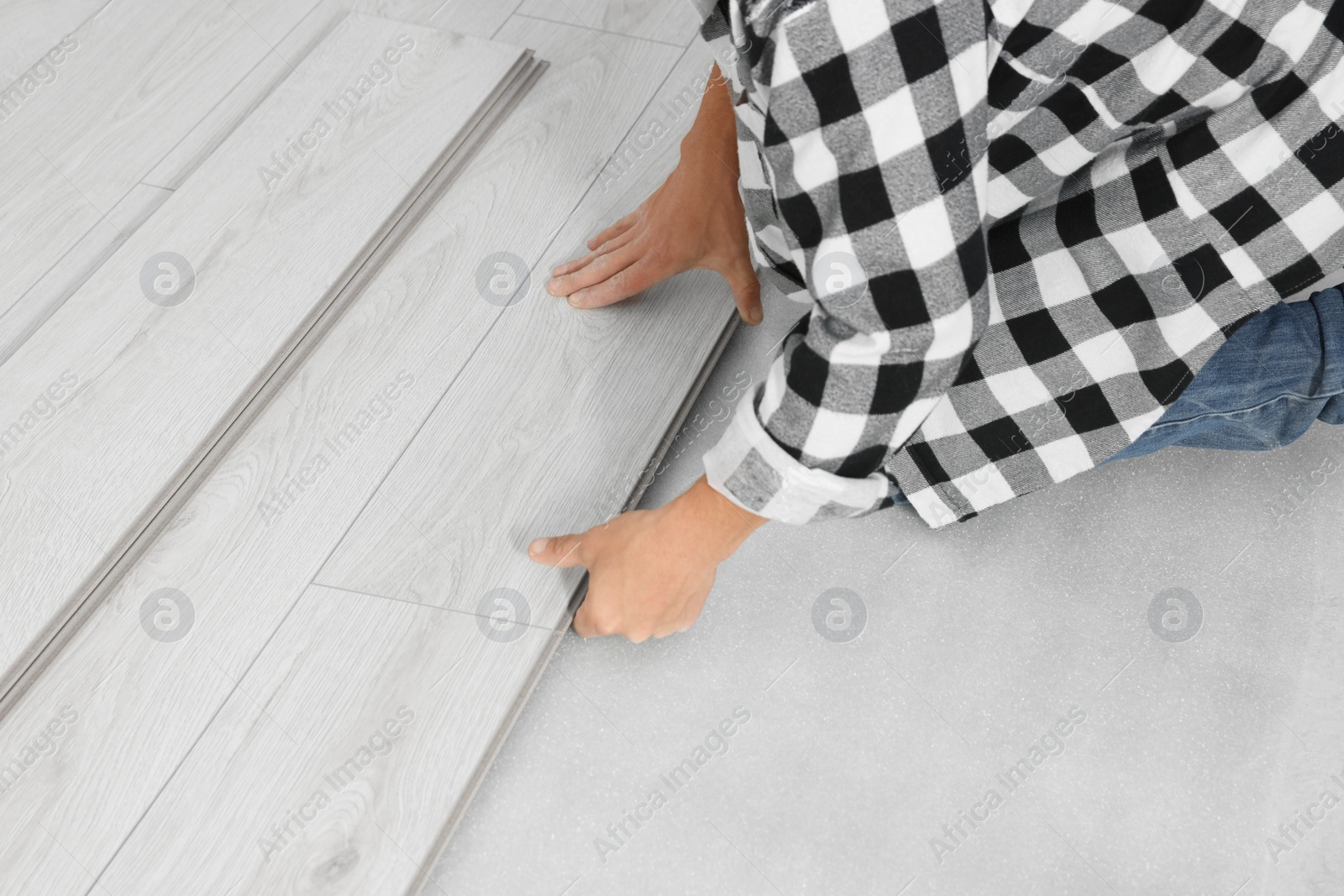 Photo of Professional worker installing new laminate flooring, closeup