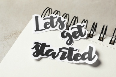 Photo of Sheets of paper with phrase Let's Get Started and notebook on grey table, closeup