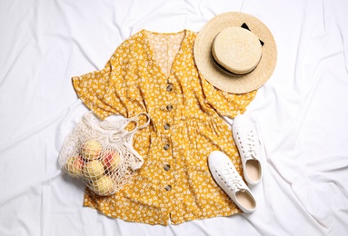 Flat lay composition with stylish yellow dress on white fabric