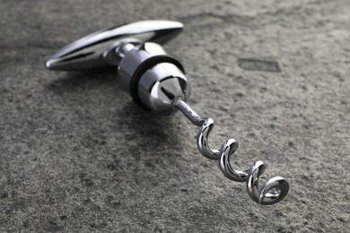 Photo of One metal corkscrew on grey textured table, closeup