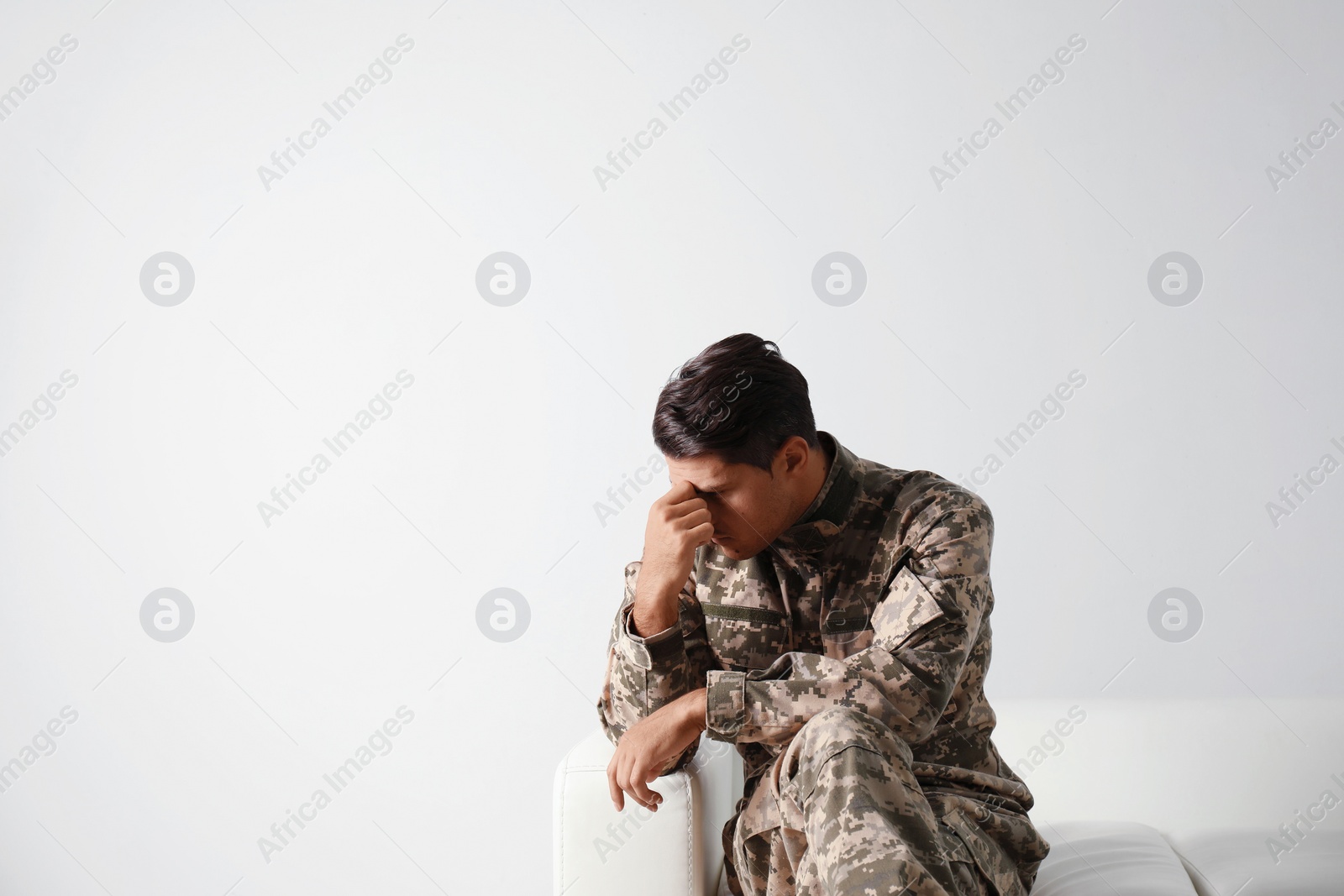 Photo of Stressed military officer sitting on sofa against white background. Space for text