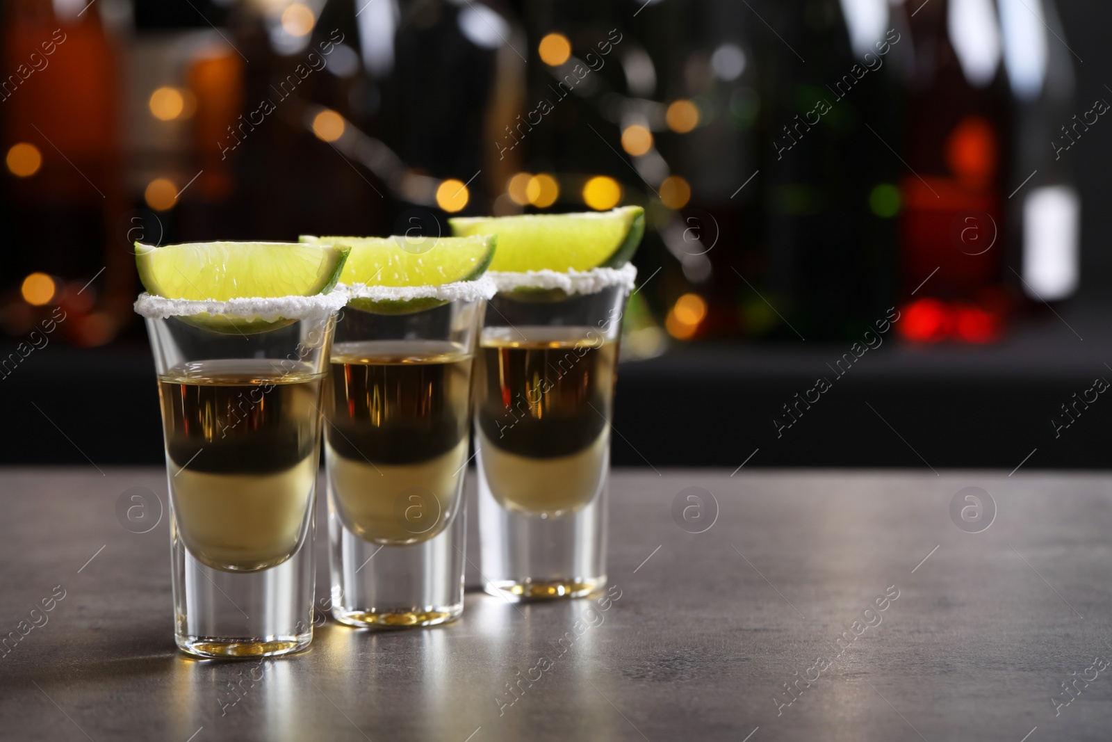 Photo of Mexican Tequila shots, lime slices and salt on bar counter. Space for text