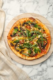 Photo of Delicious vegetarian pizza with mushrooms, vegetables and arugula on white marble table, top view