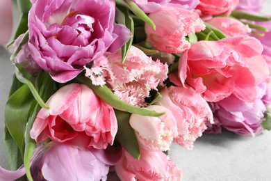 Beautiful bouquet of colorful tulip flowers on light gray table, closeup