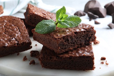 Photo of Delicious chocolate brownies with fresh mint on marble board, closeup