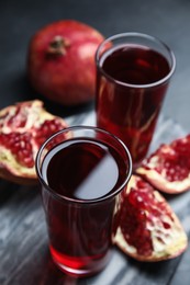 Photo of Pomegranate juice and fresh fruits on dark table