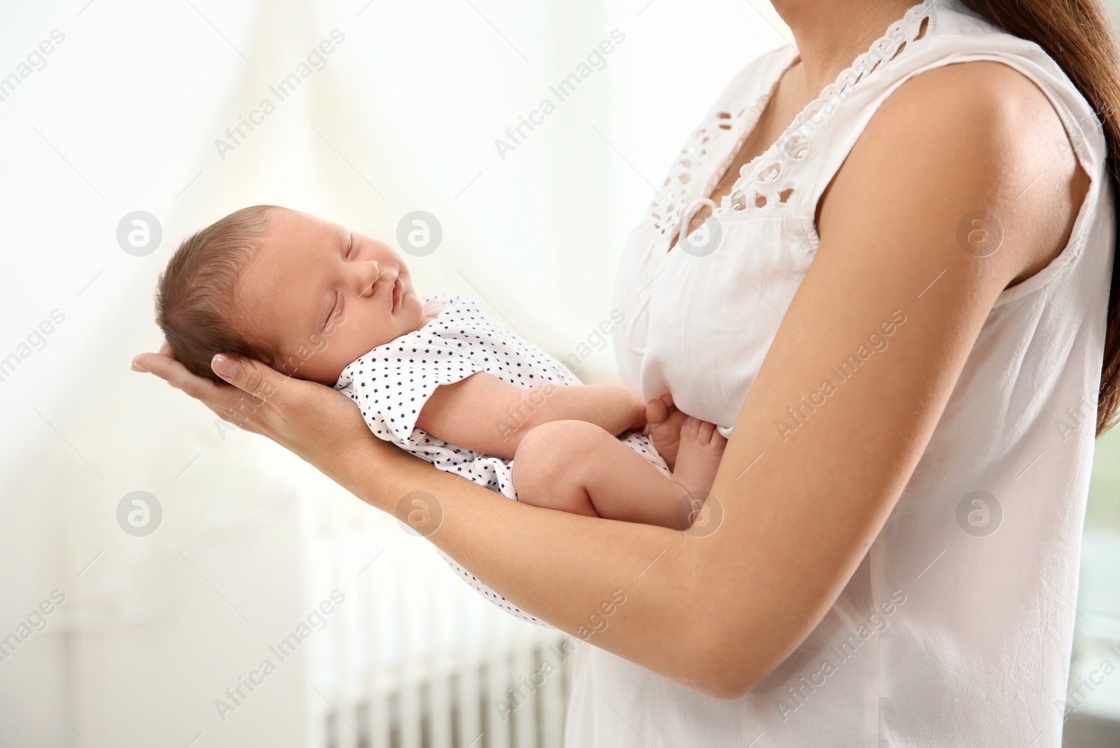 Photo of Young woman holding her newborn baby at home, closeup