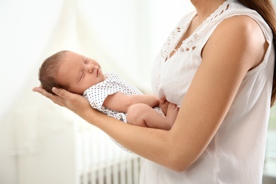 Photo of Young woman holding her newborn baby at home, closeup