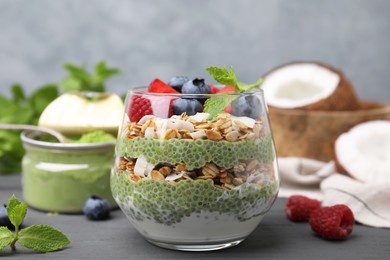 Photo of Tasty oatmeal with chia matcha pudding and berries on black wooden table, closeup. Healthy breakfast