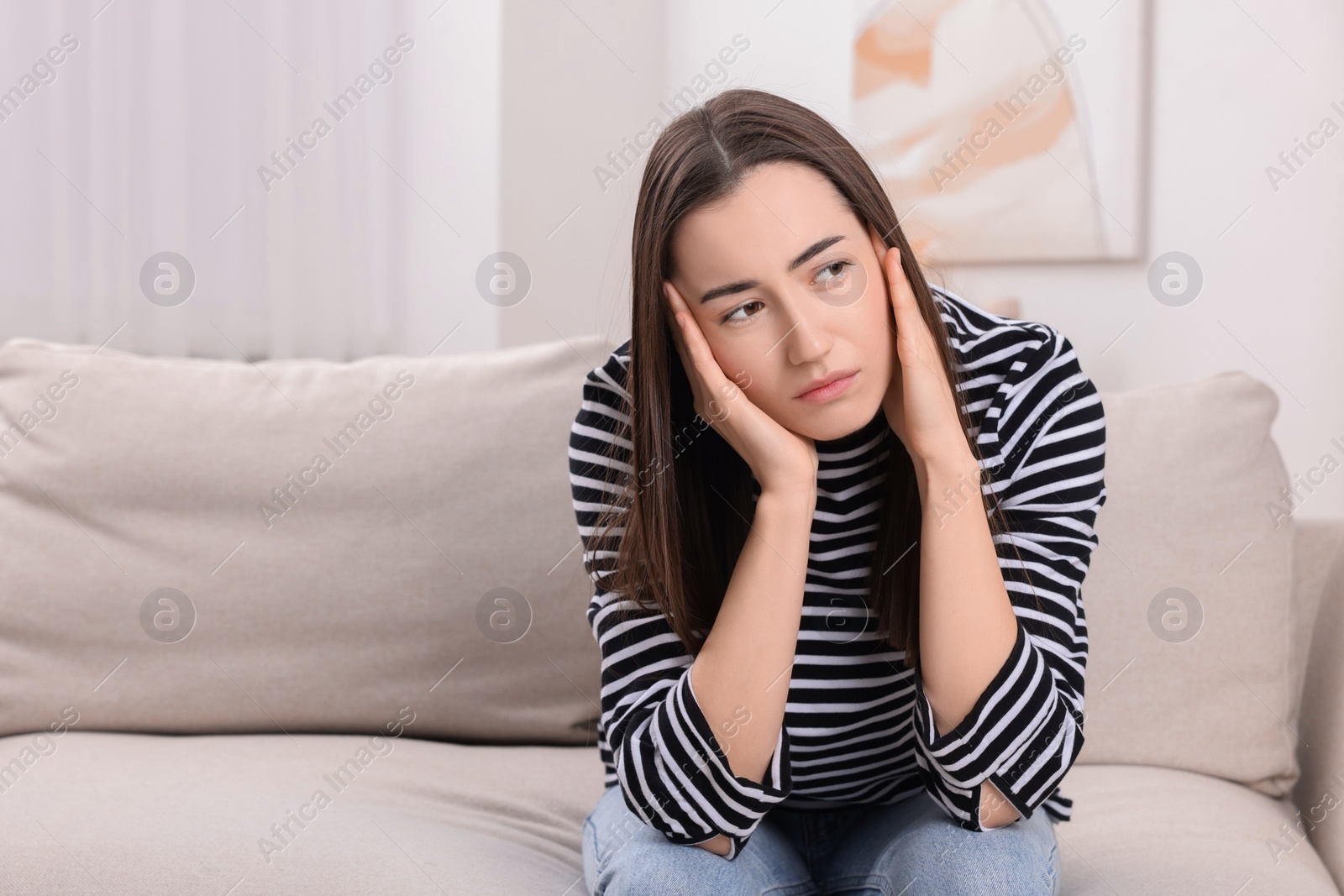 Photo of Sad woman suffering from headache on sofa indoors, space for text