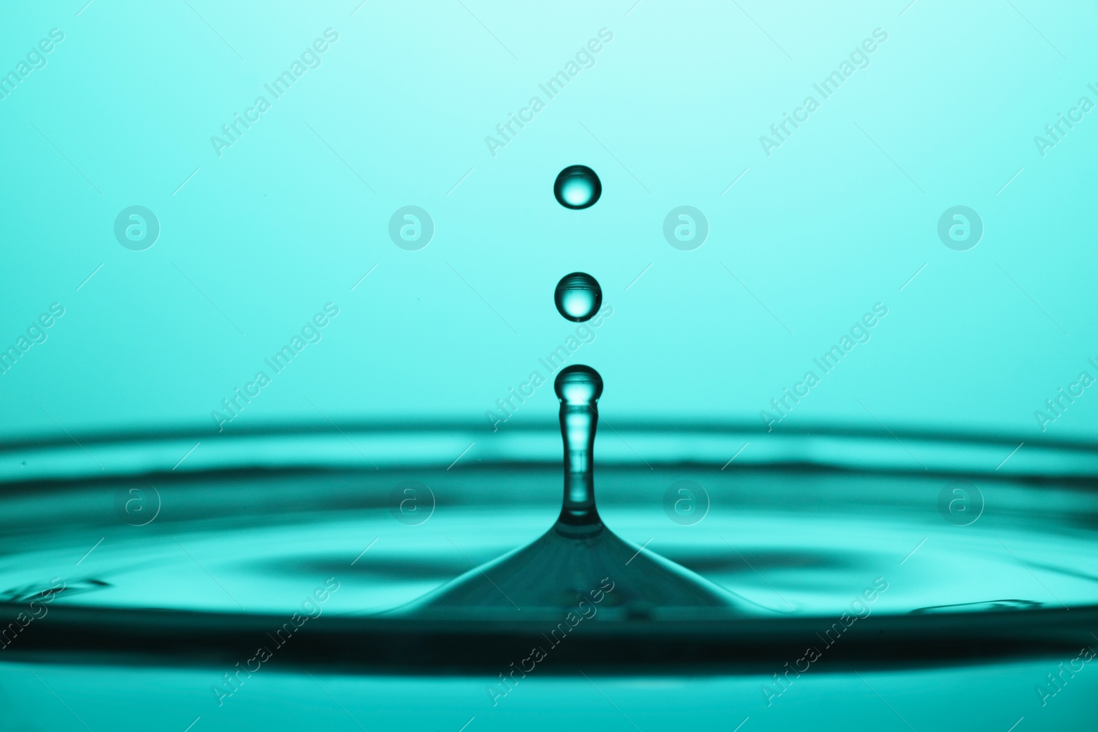 Photo of Splash of clear water with drops on turquoise background, closeup