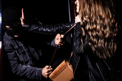 Photo of Woman fighting with thief while he trying to steal her bag outdoors at night, closeup. Self defense concept