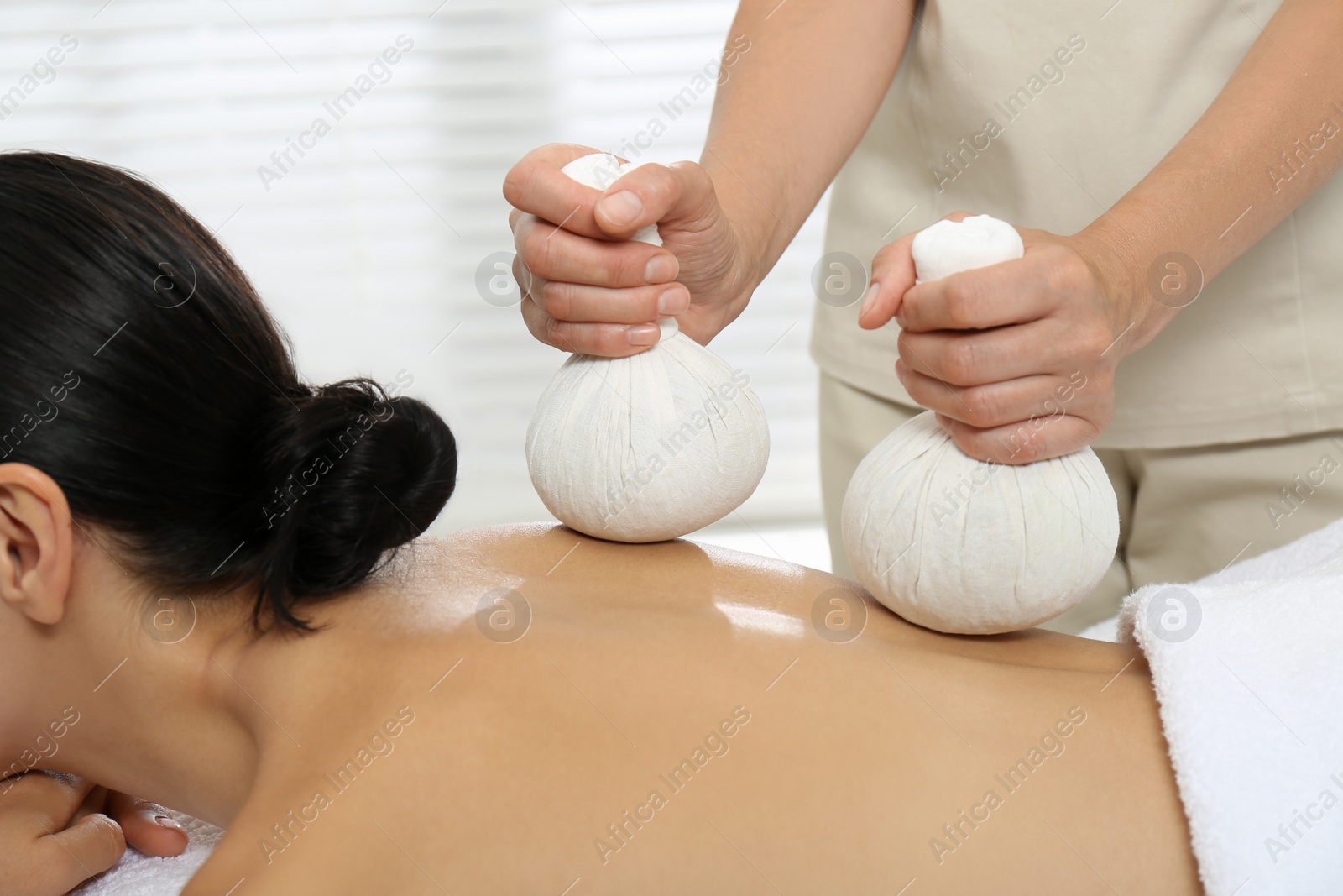 Photo of Young woman receiving herbal bag massage in spa salon, closeup