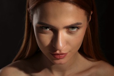 Photo of Evil eye. Young woman with scary eyes on black background, closeup