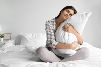 Photo of Beautiful young woman hugging pillow on bed at home
