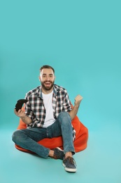 Emotional young man playing video games with controller on color background. Space for text