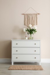 Room interior with white chest of drawers near beige wall