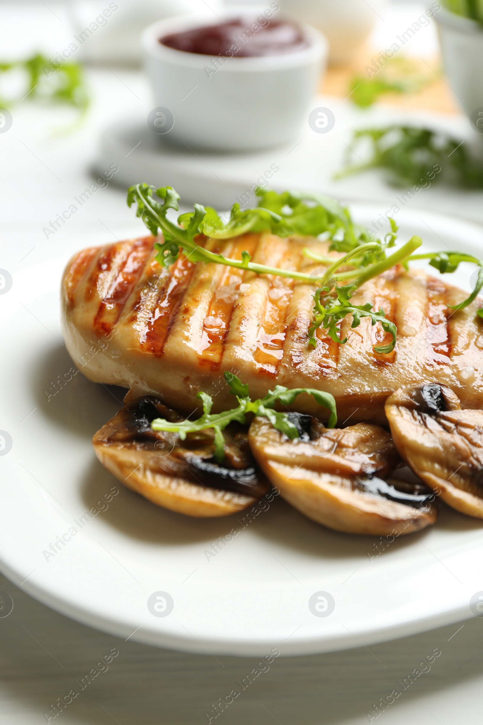 Photo of Tasty grilled chicken fillet with mushrooms and arugula on white table, closeup