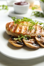 Photo of Tasty grilled chicken fillet with mushrooms and arugula on white table, closeup