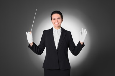 Happy professional conductor with baton on grey background