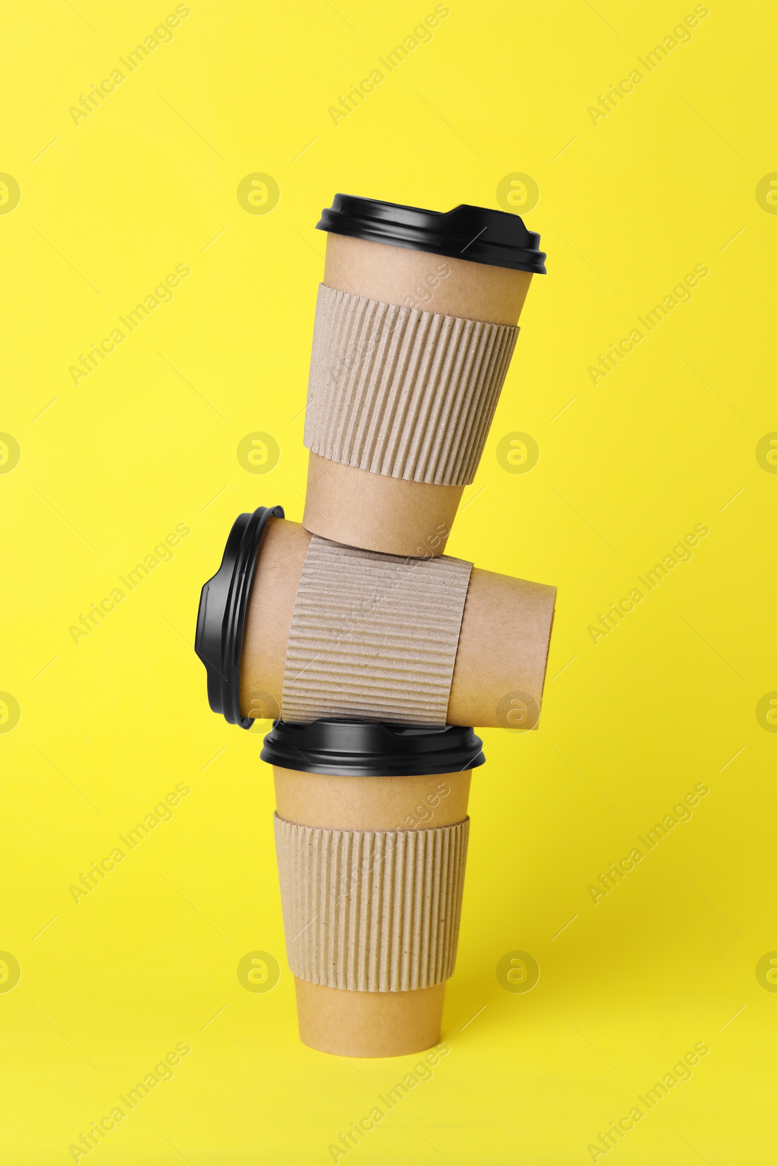 Photo of Paper cups with black lids on yellow background. Coffee to go