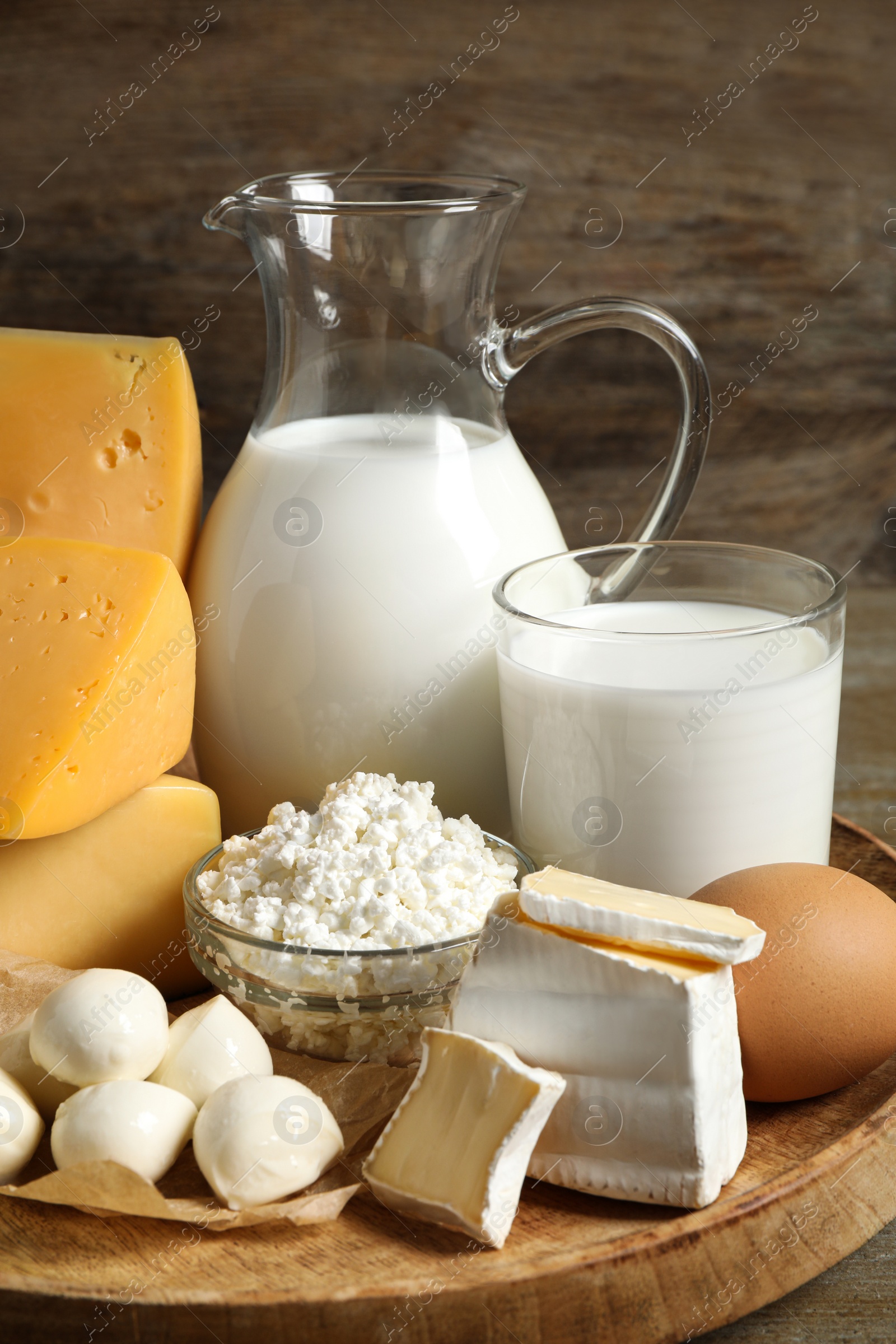 Photo of Different delicious dairy products on wooden tray