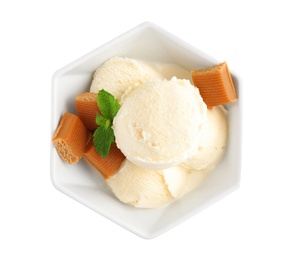 Bowl of ice cream with caramel candies and mint on white background, top view