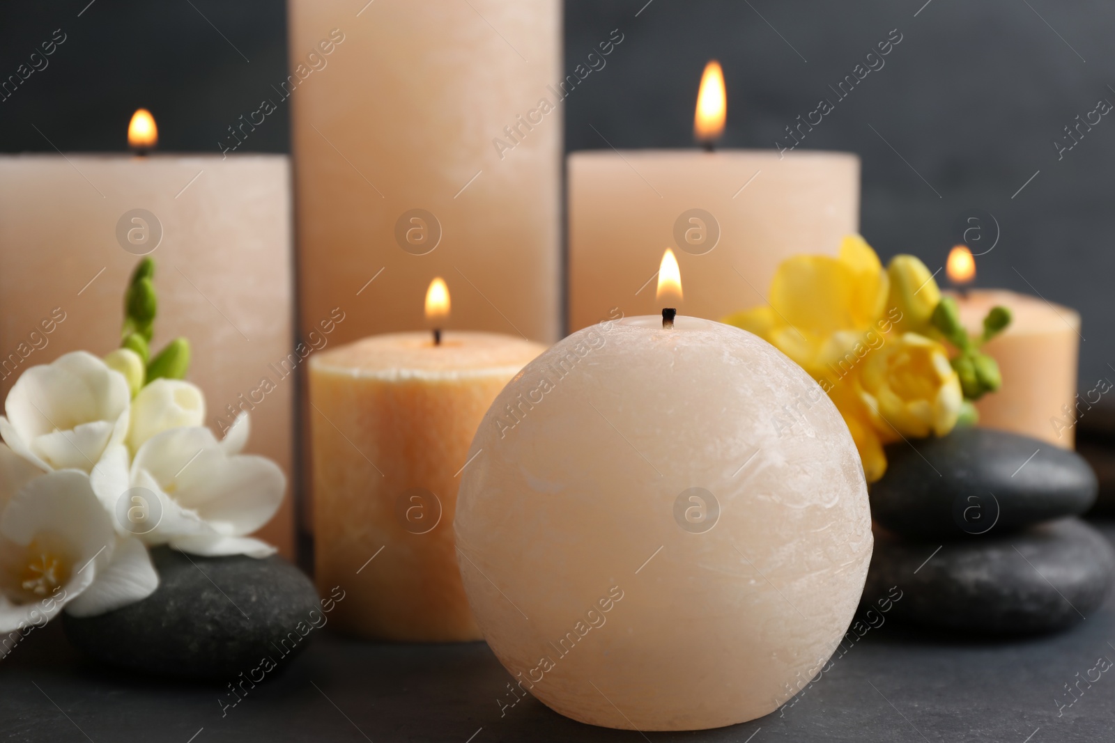 Photo of Burning candles, spa stones and flowers on table. Space for text