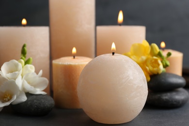 Burning candles, spa stones and flowers on table. Space for text