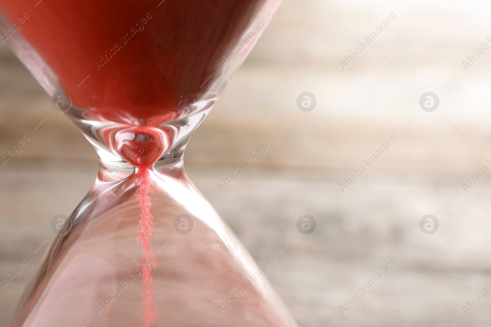 Photo of Hourglass with flowing sand on table, closeup. Time management