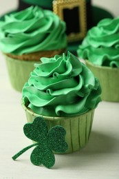 Photo of St. Patrick's day party. Tasty cupcakes with green cream on white table, closeup
