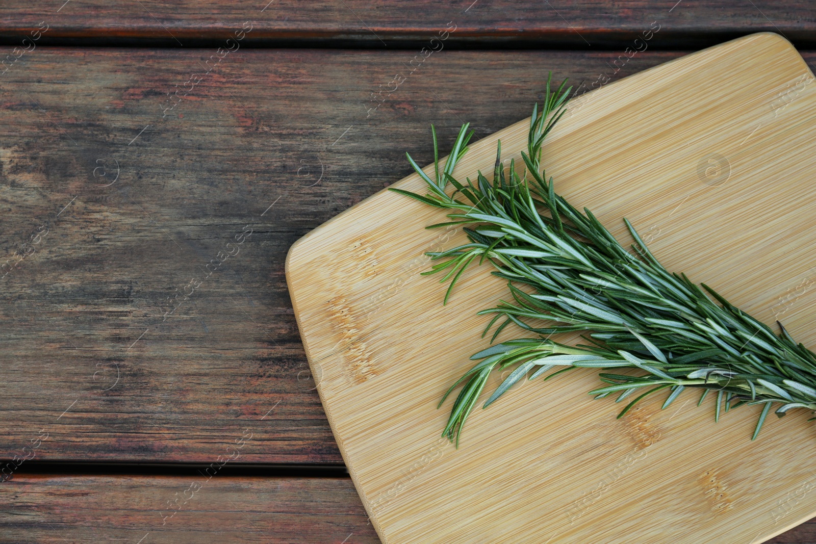 Photo of Bunch of fresh rosemary on wooden table, top view with space for text. Aromatic herb