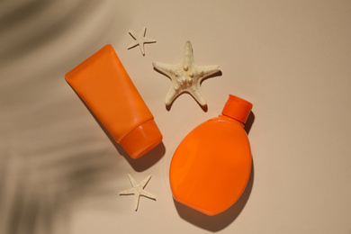 Photo of Sun protection products and starfishes on beige background, flat lay