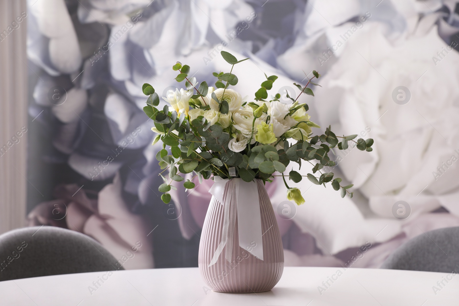 Photo of Vase with beautiful bouquet on white table indoors. Stylish interior element